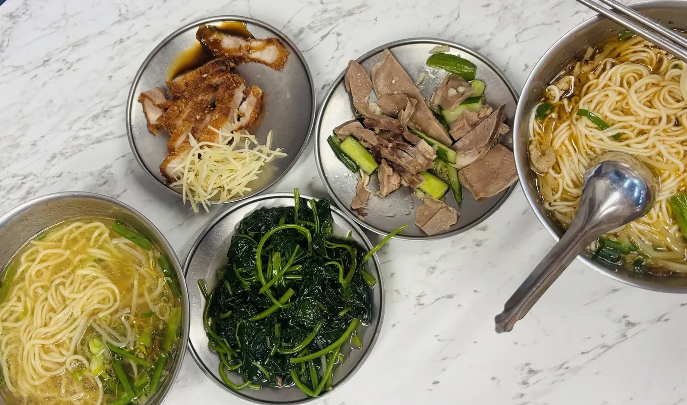 Taiwanese noodle soup and side dishes on a stainless steel table